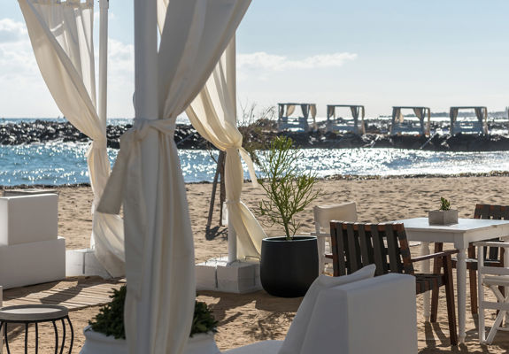 Knossos Beach Beach Life Restaurant table, chairs and couches next to the beach