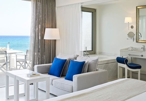 Knossos Beach Two Bedroom Suite Water Front couch, double table, bathtub and washbasin in the background