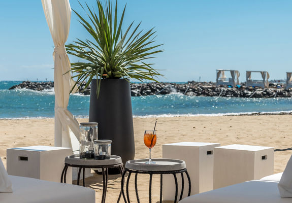 Knossos Beach Beach Life Restaurant couches and small round tables next to the beach