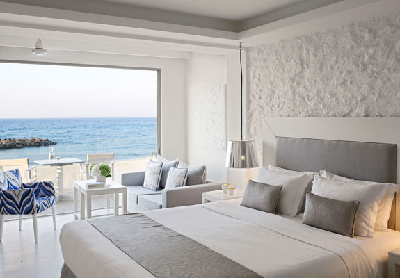 Knossos Beach Suite Waterfront big double bed, sitting area and terrace view